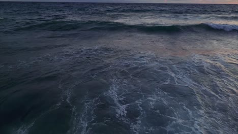 Cinematic-aerial-pullback-of-ocean-waves-crashing-against-idyllic-beach-shoreline-in-Liguria,-Italy