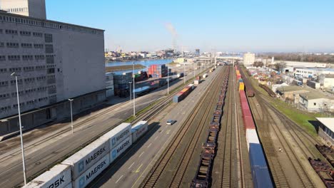 Car-touring-an-industrial-port-between-large-shipping-containers-with-a-factory-behind-it