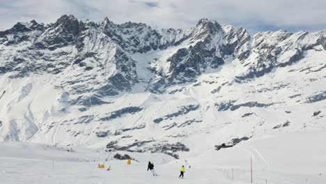 Landscape-of-skier-ski-downhill-on-a-slope-in-Cervinia-ski-resort-with-mountain-peak-background