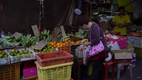 Lady-choosing-rose-apples-at-a-local-fruit-stall-in-Yaowarat-Chinatown,-Bangkok,-Thailand