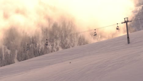 Skilift-Läuft-Bei-Sonnenaufgang-Am-Frühen-Morgen-Im-Skizentrum-In-Myrkdalen,-Norwegen-–-Idyllischer,-Stimmungsvoller-Clip-Mit-Ein-Paar-Skifahrern,-Die-Während-Der-Goldenen-Stunde-Vorbeikommen