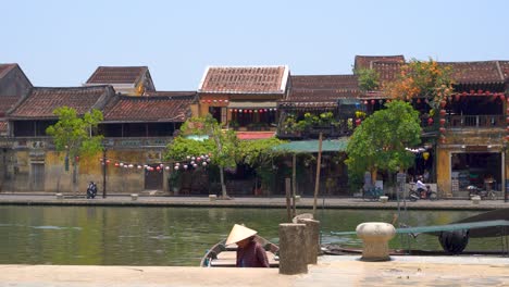 Pescador-Con-Sombrero-De-Paja-Tradicional-Con-Telón-De-Fondo-De-Casas-Adosadas-De-Hoi-An-En-Vietnam