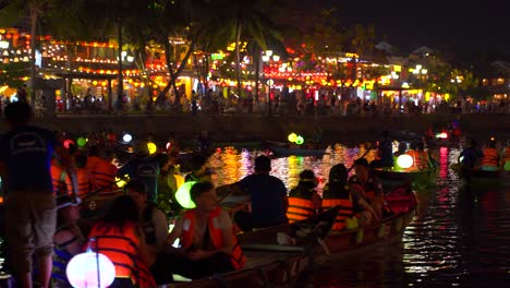 Traditionelle-Vietnamesische-Ruderboote-Auf-Dem-Fluss-Mit-Beleuchteter-Stadt-Hoi-An-In-Der-Ferne