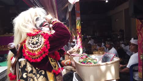 Topeng-Bailarín-Enmascarado-Se-Prepara-Para-Su-Drama-De-Danza-Usando-Peluca-Y-Flores-En-Una-Ceremonia-Tradicional-Hindú-Balinesa,-Bali-Indonesia-Con-Traje-Colorido