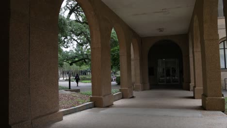 Building-with-columns-and-students-walking-by-on-the-campus-of-Louisiana-State-University-in-Baton-Rouge,-Louisiana-with-stable-establishing-shot