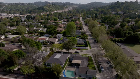 Aerial-dolly-along-LA-suburban-neighborhood-with-green-trees,-sunny-day