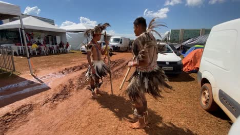 En-Un-Festival-Local-Para-Los-Indígenas-Amazónicos,-Dos-Hombres-Vestidos-Con-Trajes-Tradicionales-De-Plumas-Bailan