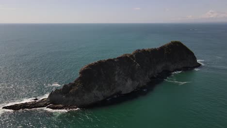 Drone-view-approaching-a-rock-formation-in-the-middle-of-the-sea