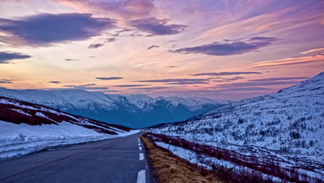 Timelapse-sunset-of-pink-and-purple-mountain-roadway-and-clouds