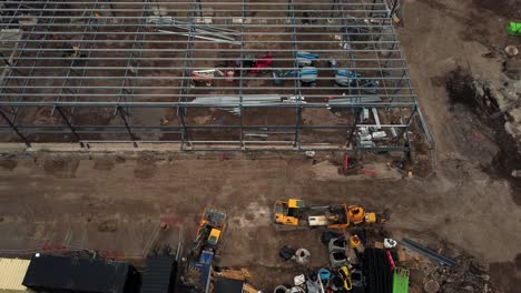 ALDI-supermarket-construction-building-site-aerial-view-tilting-downwards-industrial-framework-development,-UK