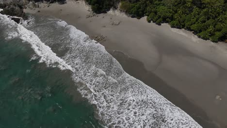 Aerial-view-of-the-waves-entering-the-coast-in-a-dark-sand-beach,-Costa-Rica