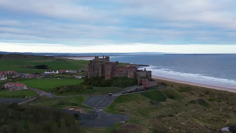 Zoom,-ascend,-rotate-orbit-around-the-stunning-Bamburgh-Castle-in-Northumberland-showing-the-breathtaking-scenery-of-this-stretch-of-the-North-Sea-coast-with-views-of-Lindisfarne-Island