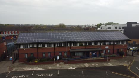 Widnes-town-police-station-with-solar-panel-renewable-energy-rooftop-in-Cheshire-townscape-aerial-rising-up-tilt-down-view