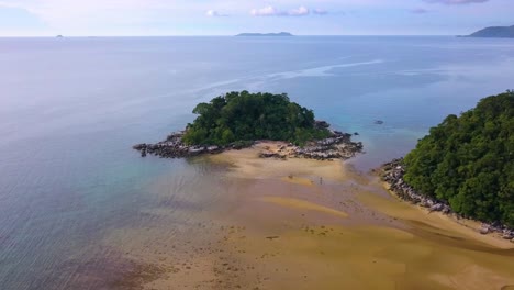 Zoom-out-aerial-shot-of-a-small-rock-island-with-trees-at-Kampung-Paya-in-Tioman-Island,-Malaysia