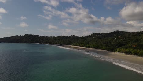 Drone-overflying-the-blue-water-ocean-towards-the-coast,-Costa-Rica