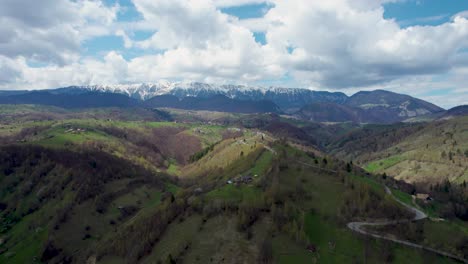 Captivating-Aerial-Shot-of-Piatra-Craiului-Mountain-Range-Against-a-Majestic-Azure-Sky,-Set-Amidst-Verdant-Hills-of-Transylvania,-Romania---In-the-Enchanting-Regions-of-Moieciu,-Rucar,-and-Bran