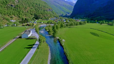 Aerial-dolly-follows-meandering-river-cutting-through-green-fields-and-valley