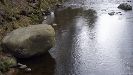 Static-shot-of-a-large-boulder-next-to-a-river