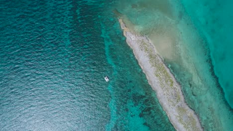 Aerial-Top-Down-Drone-View-of-Bahamas-Deserted-Island-with-Solitary-Sailboat-and-Crystal-Water
