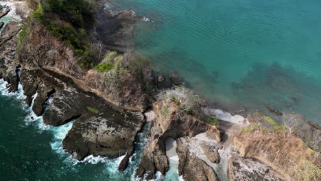 Aerial-view-of-a-rocky-cliff-in-a-tropical-beach-in-Playa-Blanca,-Costa-Rica