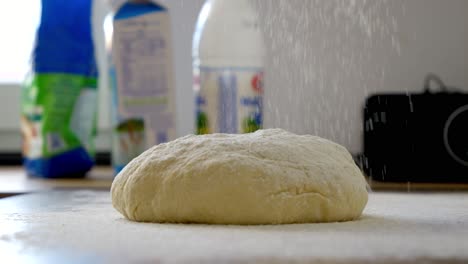 Sprinkling-flour-onto-dough-prepared-for-baking-buns