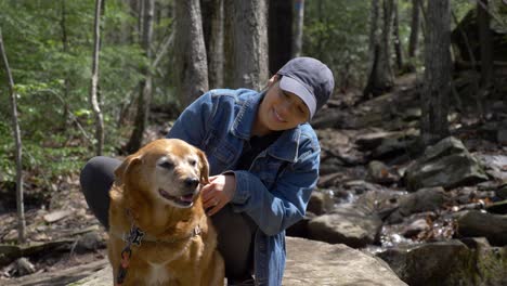 Pretty-young-diverse-woman-petting-her-senior-dog-outdoors-in-nature