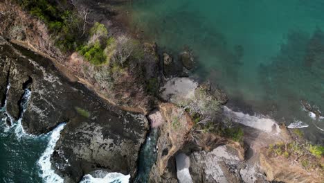 Aerial-top-down-view-of-a-rocky-cliff-dividing-two-beaches-in-Playa-Blanca,-Costa-Rica