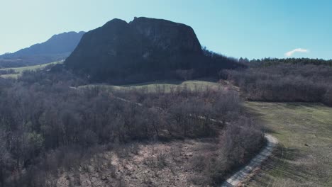 Aerial-footage-of-Pietra-Perduca,-volcanic-rock,-church-set-at-top-stone-immersed-in-countryside-landscape,-couple-of-tourist-with-dog-walking,,-Emilia-Romagna,-Italy