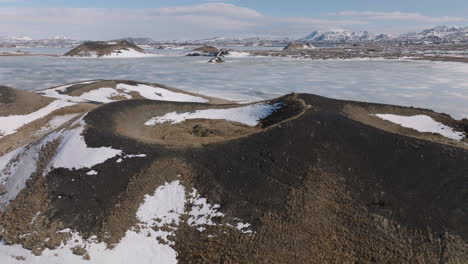 Vista-Aérea-De-La-Zona-Del-Lago-Mývatn-En-El-Norte-De-Islandia-En-Un-Día-Soleado-De-Invierno,-Cráteres-Volcánicos-Y-Agua-Congelada