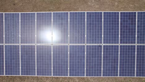 Aerial-top-down-view-Along-Solar-panels-field-with-sun-reflections,-Portugal