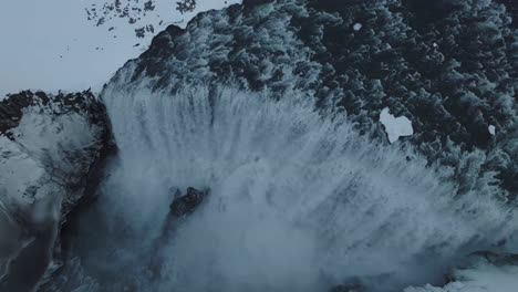 Isländischer-Wasserfall-In-Der-Wintersaison,-Vogelperspektive-Auf-Gletscherwasser-Und-Verschneite-Landschaft