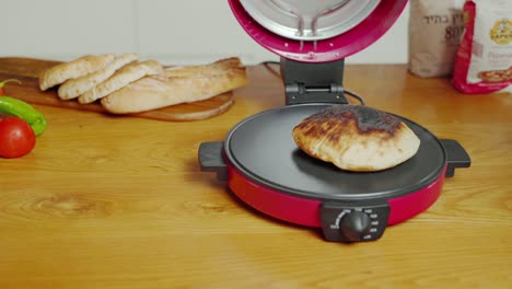 A-stationary-shot-of-an-electric-bread-maker-machine-where-a-hand-opens-the-lid-and-reveals-the-toasted-bread-inside