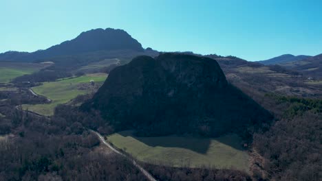 Aerial-footage-of-Pietra-Perduca-and-Barcellara,-volcanic-rocks,-church-set-at-top-stone-immersed-in-countryside-landscape,-cultivated-land-in-Val-Trebbia-Bobbio,-Emilia-Romagna,-Italy