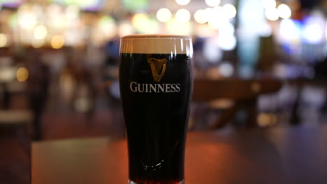 Ein-Pint-Guinness-Stout-Ale-Bier-Auf-Einem-Tisch-In-Einem-Irish-Pub-Am-St.-Patrick&#39;s-Day-In-Irland-Mit-Kunden,-Die-Vorbeigehen
