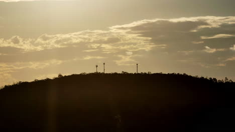Funktürme-Silhouette-Auf-Dem-Gipfel-Des-Berges-Bei-Sonnenuntergang-Mit-Wolken,-Die-über-Den-Himmel-Ziehen,-Drohne-4k
