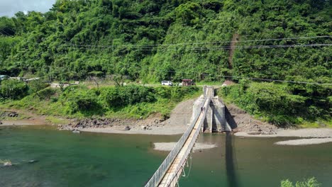 Persona-Caminando-Sobre-Un-Puente-Colgante-De-Madera-Que-Cruza-El-Río-En-Catanduanes,-Filipinas