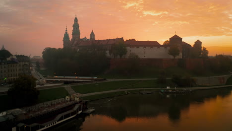Drone-footage-of-Wawel-Royal-Castle-at-magic,-cloudy-dawn-with-soft,-morning-sunlight,-Krakow-,-Poland