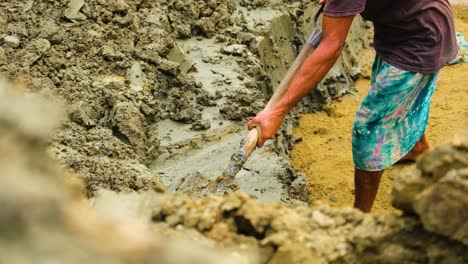 Barefoot-Bangladesh-man-shovels-wet-soil-for-use-in-brick-field