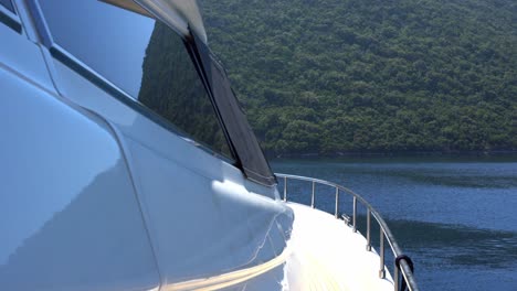 Detail-of-Yacht-at-Sea-with-Green-Forested-Mountain-Coastline