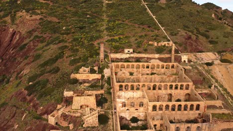 Remaining-ruins-building-of-mining-industry-in-Nebida,-Sardinia,-aerial-reveal