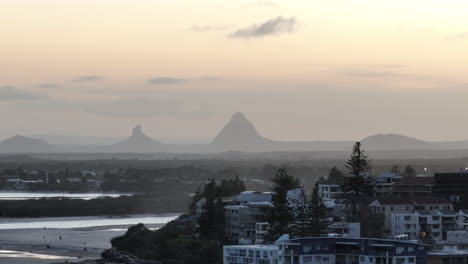 Telephoto-Drone-View-Glasshouse-Mountains-On-Hazy-Sunset-Horizon,-4K-Sunshine-Coast-Australia