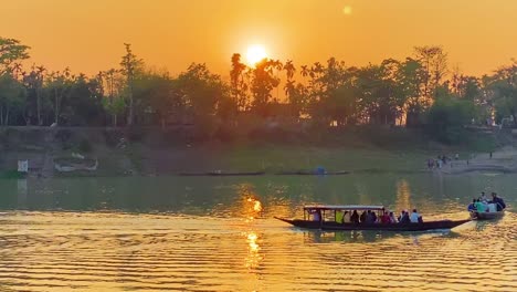 Zwei-Passagierboote-Fahren-Mit-Menschen-Beladen-Durch-Den-Fluss-Surma,-Im-Hintergrund-Ist-Ein-Wunderschöner-Goldener-Sonnenuntergang-Zu-Sehen