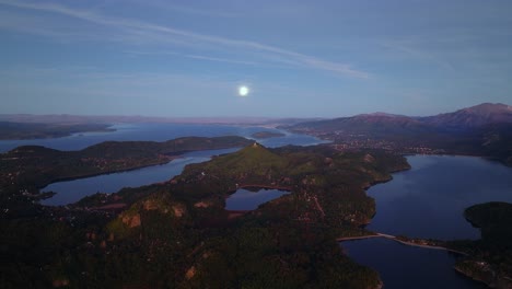 Aerial-View-of-Nahuel-Huapi-Lake-Near-Bariloche,-Rio-Negro,-Argentina-In-The-Evening-With-The-Full-Moon-On-The-Horizon