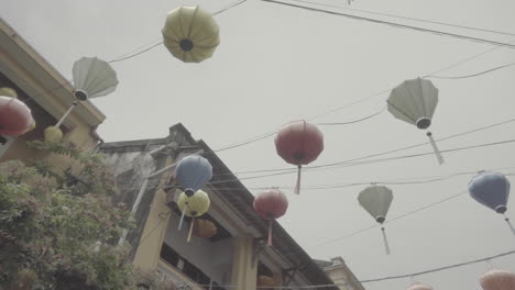 Low-angle-shot-of-the-hanging-colorful-lights-in-Hoi-An-Vietnam-on-a-cloudy-grey-day-hanging-above-the-city-LOG