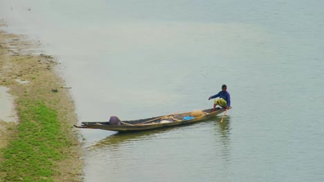 Pescador-Asiático-Amarrando-O-Saliendo-En-Canoa-Desde-La-Orilla-Del-Río.