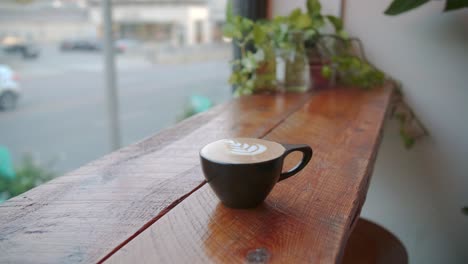 Latte-coffee-cup-art-on-wooden-bench-overlooking-street-below