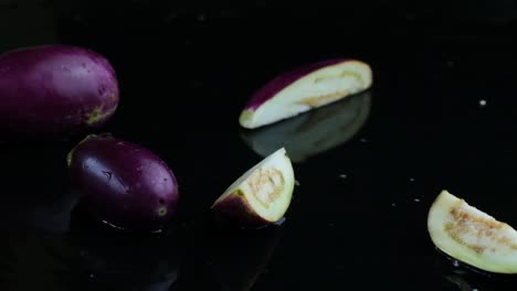 Aubergine-or-eggplants-dropped-in-a-puddle-of-water-reverse-and-fly-into-the-top-above