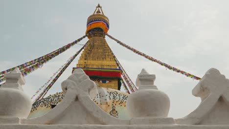 Clip-Panorámico-Mirando-Hacia-Arriba-Al-Elaborado-Templo-Dorado-En-Katmandú,-Nepal,-Con-Decoraciones-Blancas-Talladas-En-Primer-Plano