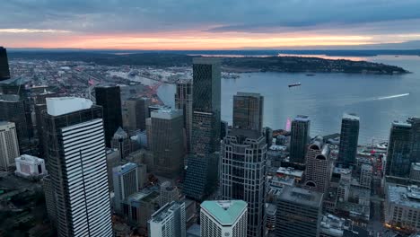 Aerial-view-of-the-sun-setting-behind-Seattle's-gloomy-downtown-skyscrapers