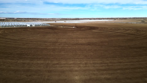 Aerial-View-Of-Empty-Plowed-Field-Near-The-Greenhouse-In-Countryside-In-Colorado